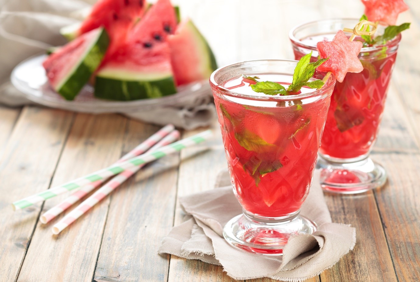 Glasses of fruit with bowl of watermelon in background