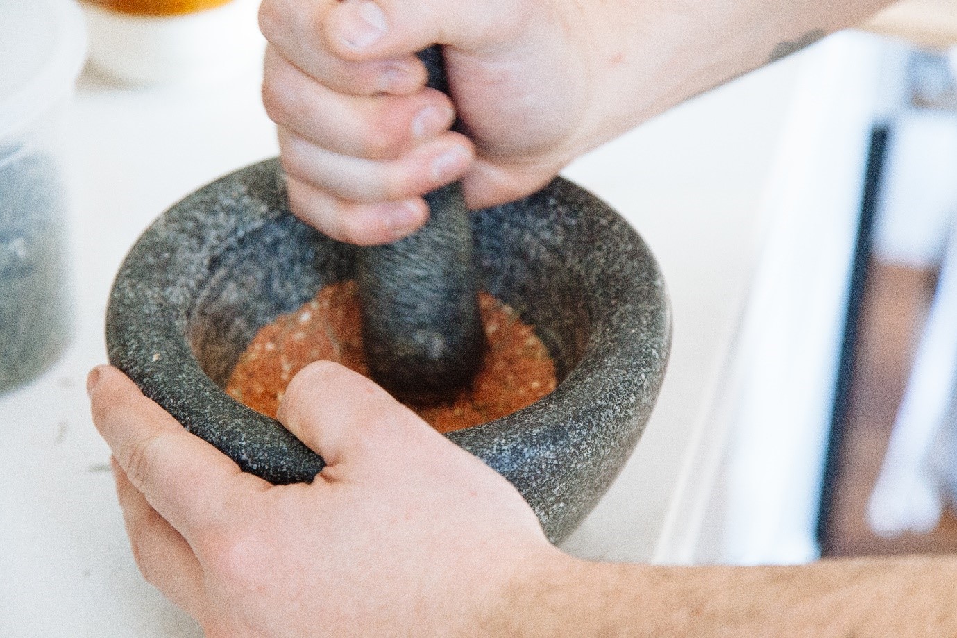 Hands crushing spices with pestle and mortar 